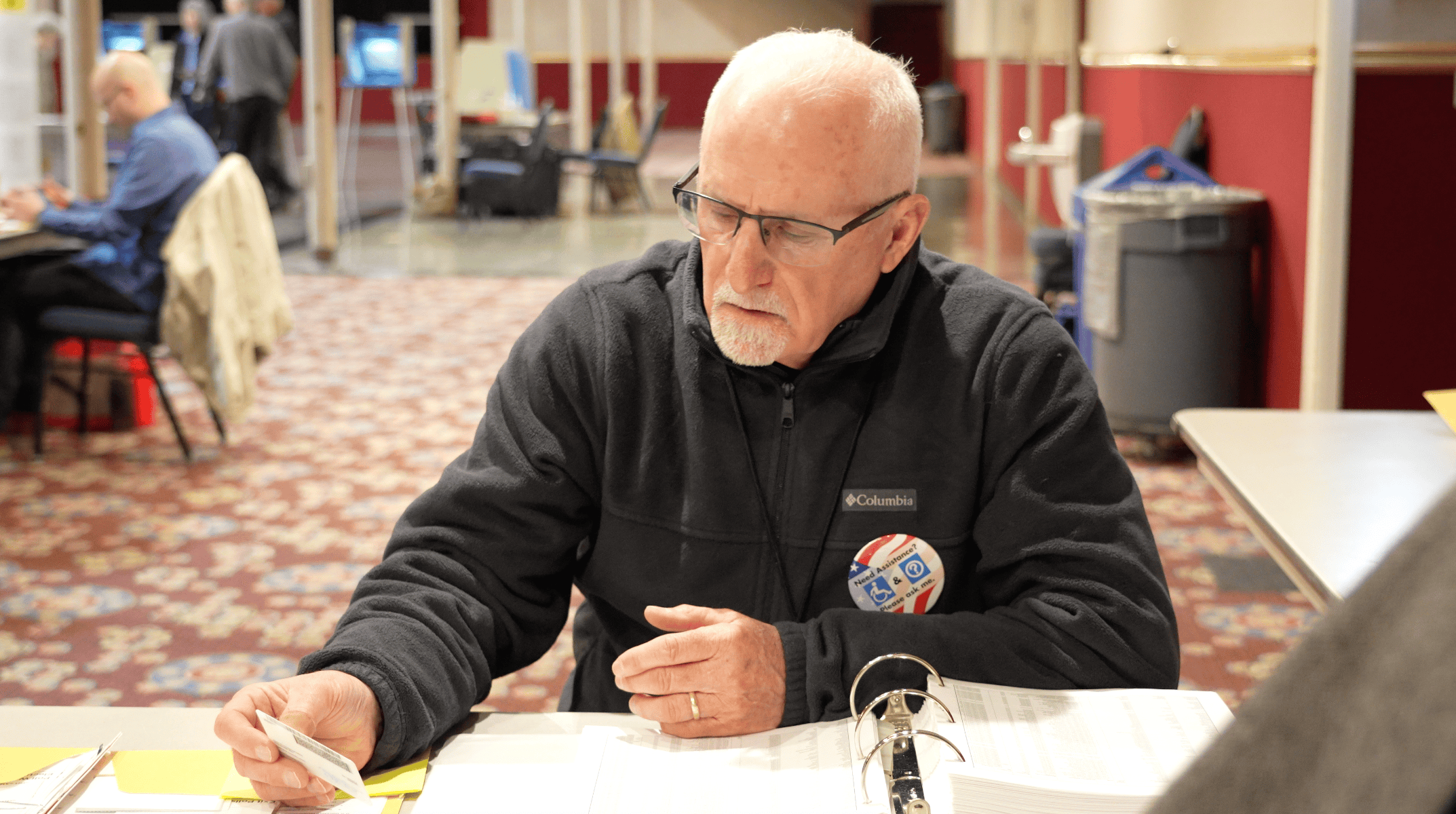 An older man at a table sorting through papers related to Montana election and voter services.