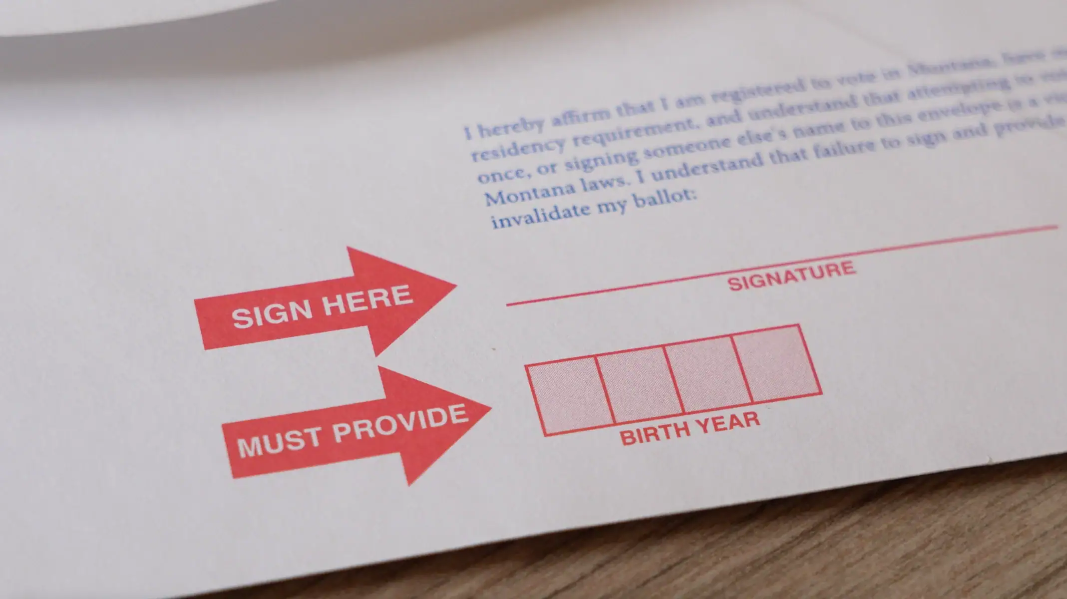 A close-up of a return envelope for absentee voting shows red arrows labeled SIGN HERE and MUST PROVIDE, pointing to boxes for SIGNATURE and BIRTH YEAR.